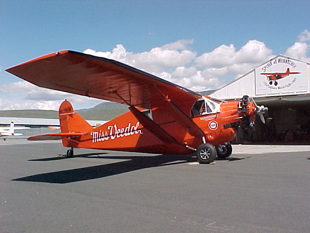 Image of a red airplane sitting in front of a hangar